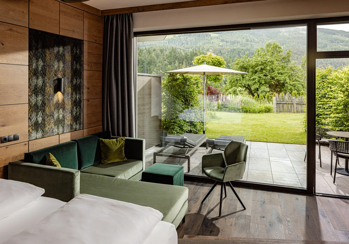 Gartensuite im Hotel Kronblick mit grünem Sofa, Terrasse mit Liegestühlen und Blick auf die Südtiroler Bergwelt
