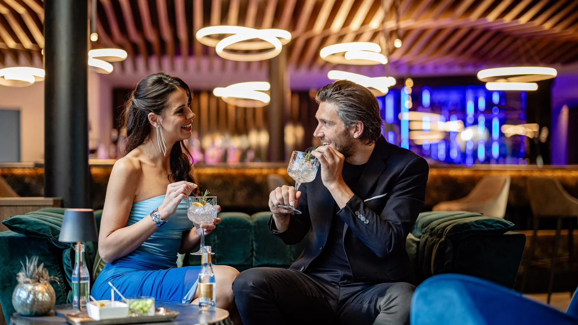 Paar trinkt Gin-Tonic-Cocktails auf Samtsofas in der stilvollen Bar-Lounge des Hotel Kronblick in Südtirol