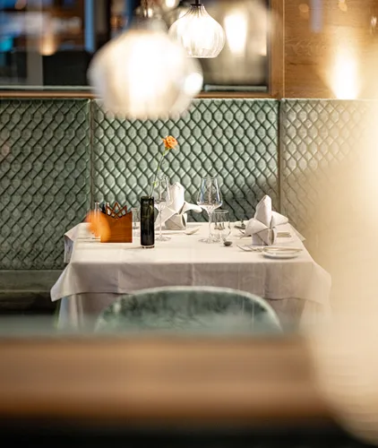 Romantisch gedeckter Tisch für zwei mit Blumenvase und Pendelleuchte im Restaurant des Hotel Kronblick Pustertal