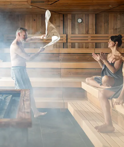 Aufguss-Zeremonie mit Dampf und applaudierendem Paar in der Sauna des Hotel Kronblick in Kiens
