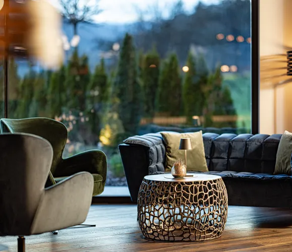 Elegante Lounge mit Samtsessel und Designertisch in stimmungsvoller Abendbeleuchtung im Hotel Kronblick