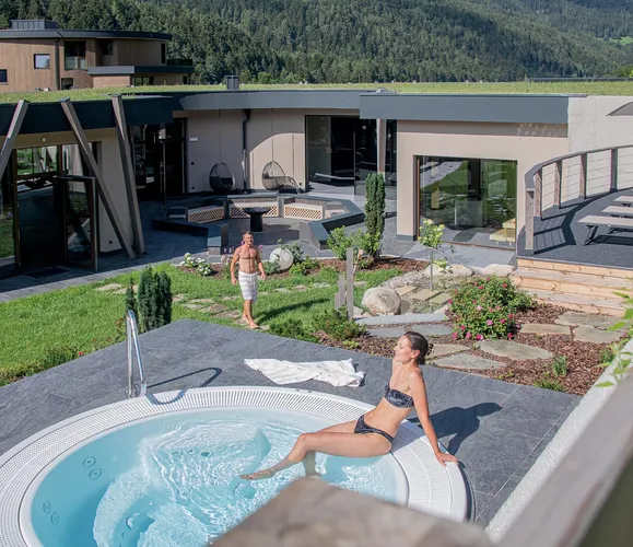 Außenansicht des Wellnessbereichs im Hotel Kronblick mit begrüntem Dach, Whirlpool und Gartenanlage in Kiens